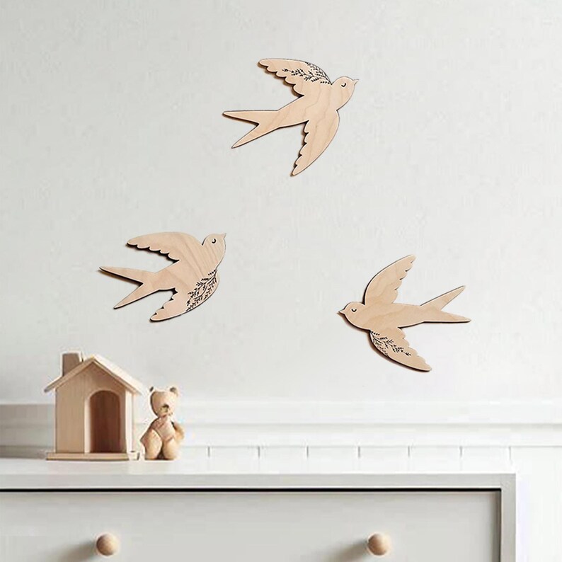 There are three wooden swallows on the wall. Swallows have floral engraving.