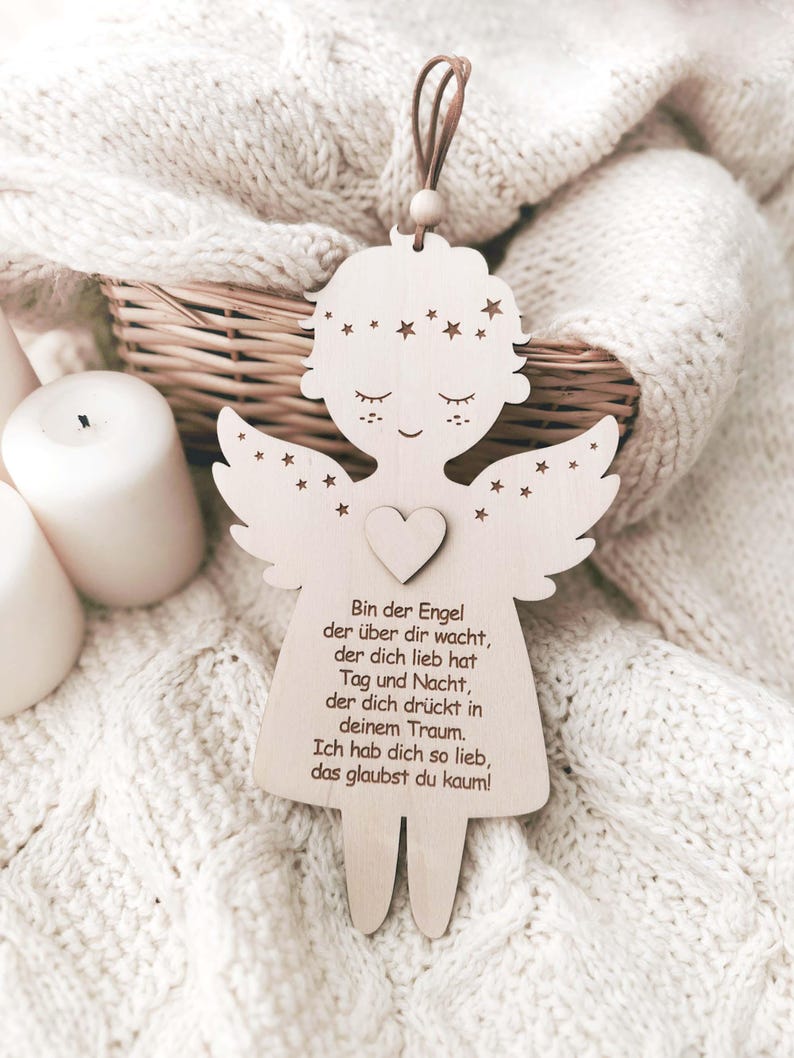 Puede incluir: Adorno de &aacute;ngel de madera con detalles de coraz&oacute;n y estrellas, con un lazo de cuero marr&oacute;n para colgar. El &aacute;ngel tiene una cara dulce y alas. Texto en alem&aacute;n grabado en el cuerpo del &aacute;ngel.