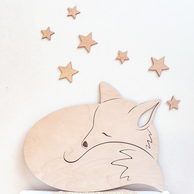 May include: A wooden cutout of a sleeping fox with a curled tail. The fox is surrounded by small wooden stars.