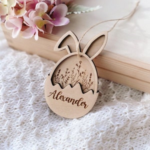 May include: A wooden Easter egg ornament with bunny ears, featuring a floral design and the name "Alexander" engraved on the front.
