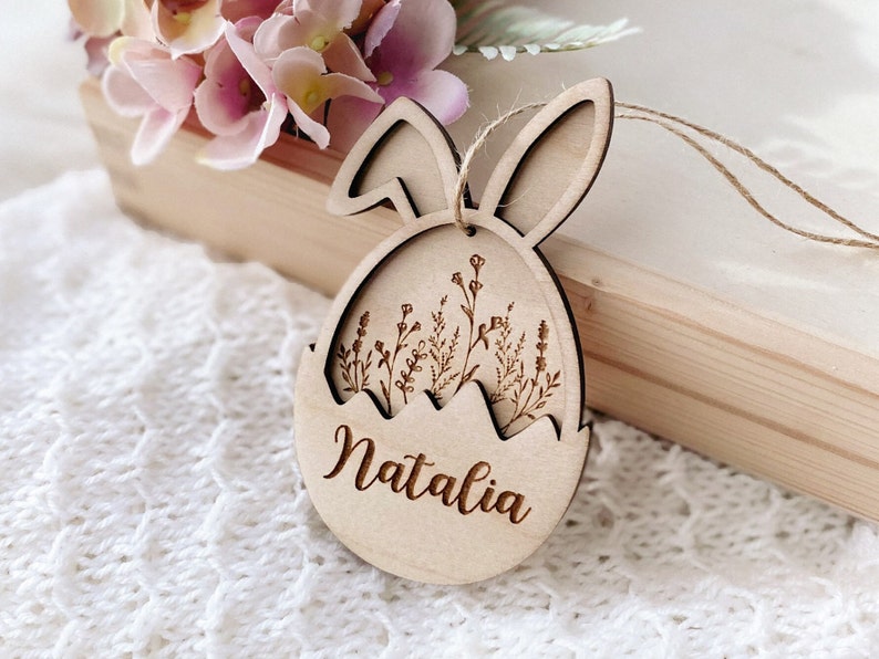 May include: Wooden Easter egg ornament with bunny ears, featuring a floral design and the name "Natalia" engraved on the front.