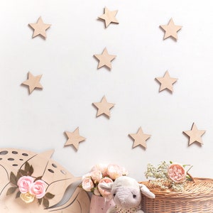 Peut inclure: Un mur blanc d&eacute;cor&eacute; d'&eacute;toiles en bois, avec un &eacute;l&eacute;phant en peluche assis sur un panier en osier. Il y a des fleurs roses dans un vase rose.