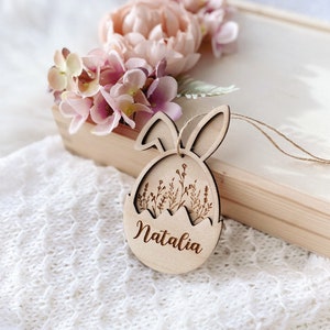 May include: Wooden Easter egg ornament with bunny ears, featuring a floral design and the name "Natalia" engraved on the front.