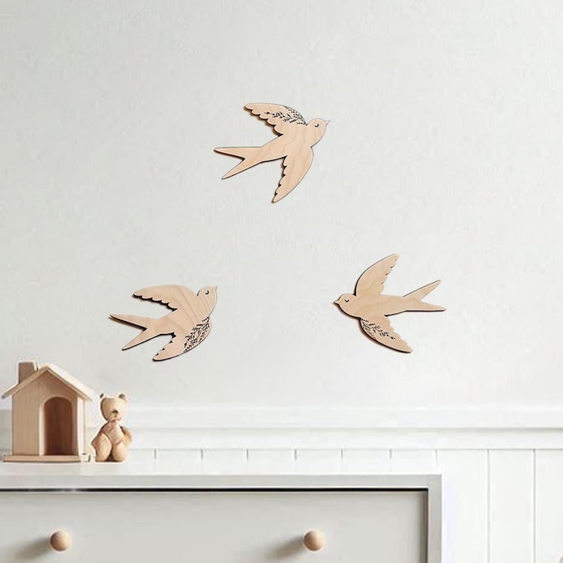 There are three wooden swallows on the wall. Swallows have floral engraving.