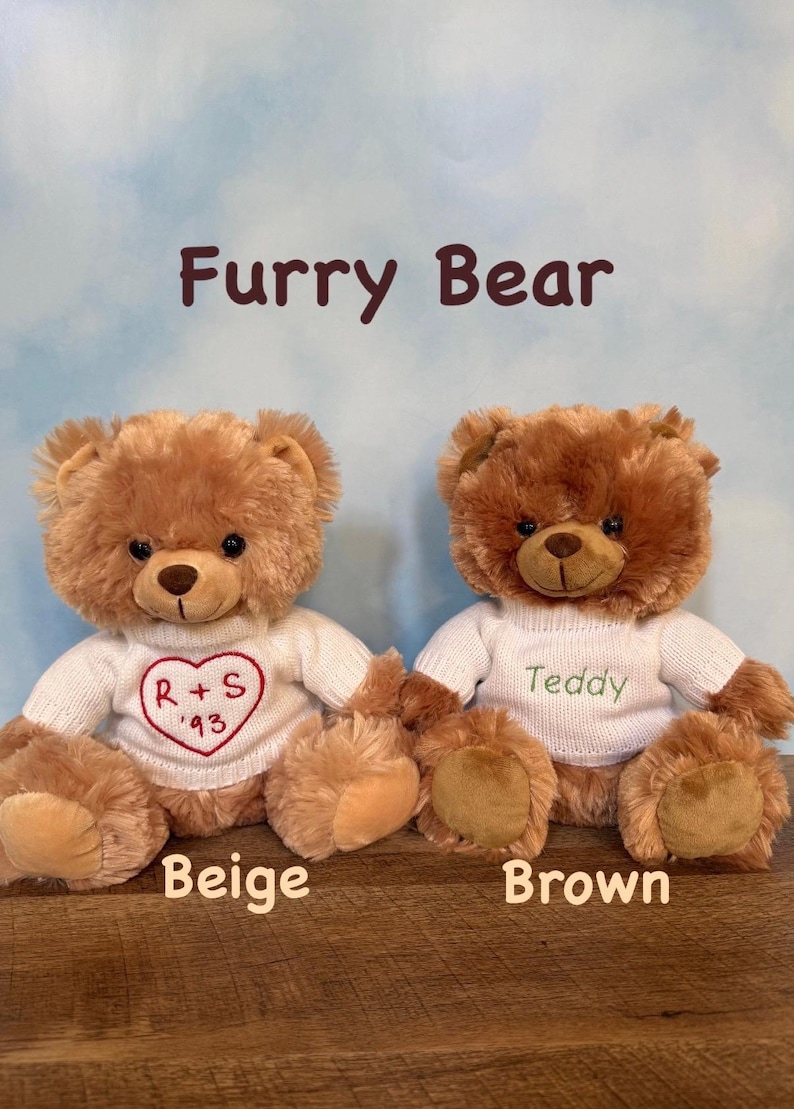 May include: Two plush teddy bears, one beige and one brown, are displayed. Each bear wears a white sweater. The beige bear's sweater has a red heart with "R + S '93". The brown bear's sweater says "Teddy". The text "Furry Bear" is above the bears.