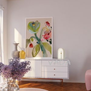 K&ouml;nnte beinhalten: Eine wei&szlig;e Kommode mit drei Schubladen und goldenen Kn&ouml;pfen. Eine wei&szlig;e Lampe mit einer geschwungenen Bogenform steht auf der Kommode. Ein gerahmtes Aquarellbild von Blumen in Rosa-, Gr&uuml;n- und Blaut&ouml;nen h&auml;ngt an der Wand &uuml;ber der Kommode. Das Bild ist auf einem beigefarbenen Hintergrund.