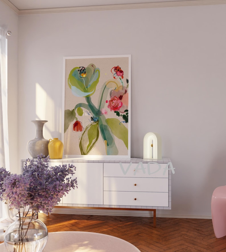 K&ouml;nnte beinhalten: Eine wei&szlig;e Kommode mit drei Schubladen und goldenen Kn&ouml;pfen. Eine wei&szlig;e Lampe mit einer geschwungenen Bogenform steht auf der Kommode. Ein gerahmtes Aquarellbild von Blumen in Rosa-, Gr&uuml;n- und Blaut&ouml;nen h&auml;ngt an der Wand &uuml;ber der Kommode. Das Bild ist auf einem beigefarbenen Hintergrund.