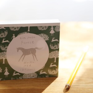Pode incluir: Um bloco de notas verde e branco com uma ilustração de um cavalo e o texto "mini forest" e "me memo" na frente.
