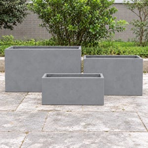 May include: A set of three rectangular planters in a solid grey finish. The planters are arranged in a tiered formation with one large, one medium, and one small container, each featuring clean, straight edges and a smooth, uniform surface.