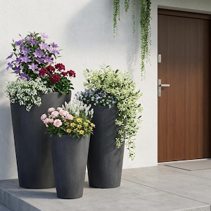 May include: Three dark grey, tall, cylindrical planters filled with colourful flowers. The flowers include purple, red, pink, yellow, and white blooms. The planters are on a concrete surface near a brown door.