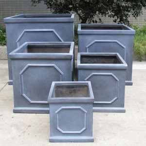 May include: A set of five square planters in varying sizes, arranged in a tiered formation. Each planter features a smooth, matte grey finish and a raised octagonal panel design on the front face, with a wide rim and a hollow, open-top interior.