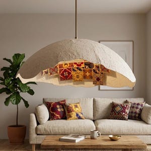 May include: A large, dome-shaped pendant light fixture with a textured, off-white exterior and a metallic rod mount. The interior of the shade features a vibrant, multi-colored mosaic pattern with red, yellow, and brown geometric tile designs.