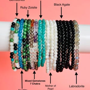 May include: A selection of beaded bracelets showcasing diverse gemstones such as mixed gemstones, amazonite, ruby zoisite, black agate, apatite, 7 chakra mixed gemstones, mother of pearl, and labradorite. Each bracelet is made with small, round beads in various colours.