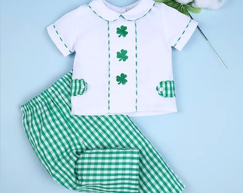 Könnte beinhalten: Ein weißes, kurzärmeliges Hemd mit einem grünen Kleeblatt-Design und einer grün-weiß karierten Hose. Das Hemd hat einen Peter-Pan-Kragen und drei Kleeblätter auf der Vorderseite.