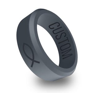以下が含まれることがあります： 片側に「CUSTOM」と刻印され、反対側に魚の形をしたシンボルが刻まれた、濃いグレーのシリコンリングです。
