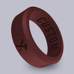 May include: A maroon silicone ring with the word "CUSTOM" engraved on the side and a screwdriver and hammer symbol engraved on the other side.