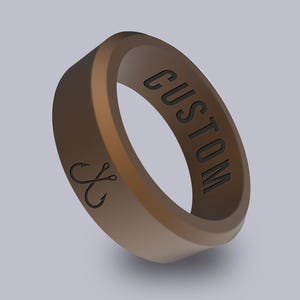 May include: A brown silicone ring with the word "CUSTOM" engraved on the side and a pair of fishing hooks engraved on the other side.