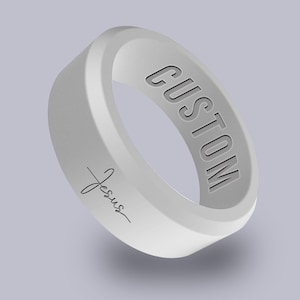May include: White silicone ring with the word "CUSTOM" engraved on the outside and the word "Jesus" engraved on the inside.