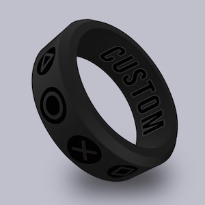 May include: Black silicone ring with the word "CUSTOM" and four symbols: a triangle, a circle, an X, and a square.