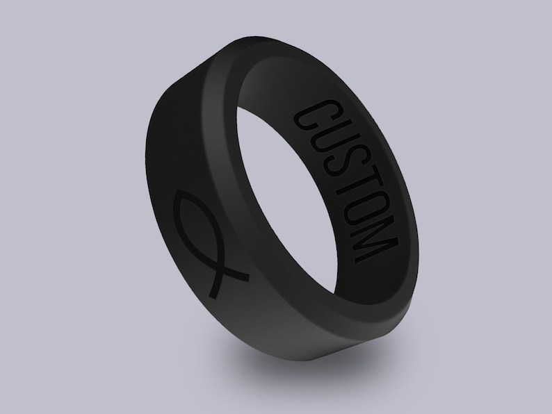 以下が含まれることがあります： 片側に「CUSTOM」と刻まれた黒いシリコンリング。反対側には魚のシンボルが刻まれています。