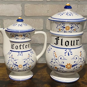 K&ouml;nnte beinhalten: Zwei antike Keramikdosen mit blauen und wei&szlig;en Blumenmustern. Die gr&ouml;&szlig;ere Dose ist mit "Mehl" und die kleinere Dose mit "Kaffee" beschriftet.