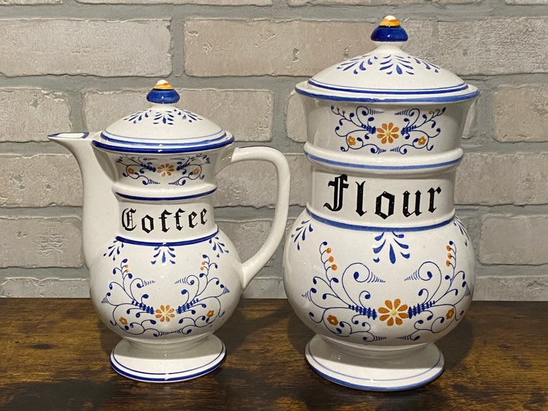 K&ouml;nnte beinhalten: Zwei antike Keramikdosen mit blauen und wei&szlig;en Blumenmustern. Die gr&ouml;&szlig;ere Dose ist mit "Mehl" und die kleinere Dose mit "Kaffee" beschriftet.
