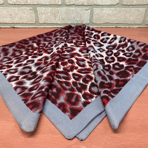 May include: A gray and red leopard print bandana with a gray border.