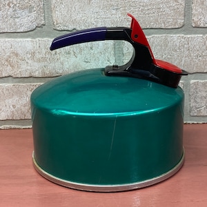 May include: A teal blue enamel tea kettle with a black and red handle. The kettle has a silver rim around the base.