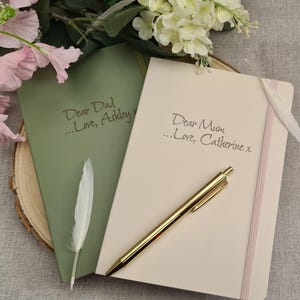 May include: Two blank journals with personalised messages. The green journal says "Dear Dad...Love, Ashley" and the cream journal says "Dear Mum...Love, Catherine x".