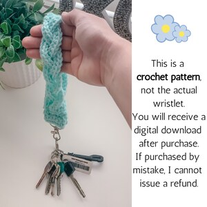 May include: A crochet pattern for a wristlet, shown in a light blue color. The pattern is for a digital download, not the actual wristlet. The text in the image reads: "This is a crochet pattern, not the actual wristlet. You will receive a digital download after purchase. If purchased by mistake, I cannot issue a refund."