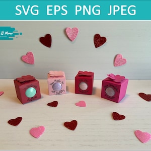 May include: Four pink and red gift boxes with a heart-shaped window on the front. Each box contains a bath bomb with a different message: "Valentine's Day", "You Make Me Smile", "You Are My Sunshine", and "Happy Valentine's Day".