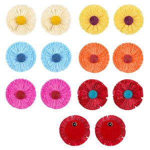 May include: A collection of colorful, round, raffia-style decorative elements. The assortment includes various colors such as yellow, blue, orange, pink, and red. Each piece has a central, contrasting color and a fringed outer edge, resembling flowers.
