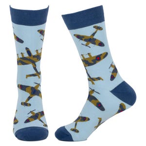 Peut inclure: Paire de chaussettes bleu clair avec des bordures, talons et pointes bleu marine. Les chaussettes présentent un motif répété d'avions de chasse marron et vert avec des détails rouges. Fabriquées dans une matière douce et confortable.
