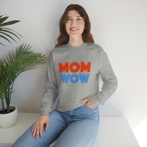 May include: A grey sweatshirt with the text "MOM WOW" in red and blue letters. The letters are outlined in white.