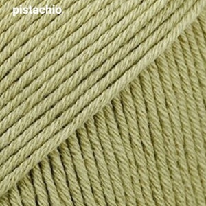Puede incluir: Primer plano de una madeja de hilo de color pistacho. El hilo es suave y texturizado, con un brillo sutil.