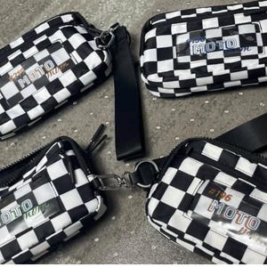 May include: Four black and white checkered fanny packs with the text "MOTO" in a clear rectangular patch. Each bag has a different number on the patch. One bag has a black strap attached. The bags are on a gray surface.