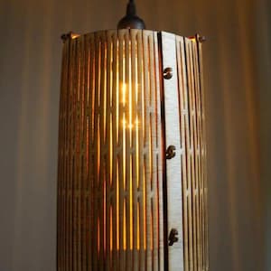 May include: A wooden pendant light with a geometric pattern. The light is on and casting a warm glow.