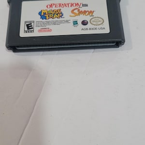 May include: A black Game Boy Advance cartridge featuring the game "Operation Mouse Trap Simon". The label includes the game title in a colorful design, the Nintendo logo, and an ESRB rating.