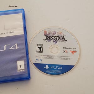 May include: A blue PlayStation 4 game case with the text "PreOwned" and "Dissidia Final Fantasy <PS4>" on the front. The game case is next to a blue and white PlayStation 4 game disc with the text "DISSIDIA FINAL FANTASY" and "SQUARE ENIX" on the front.