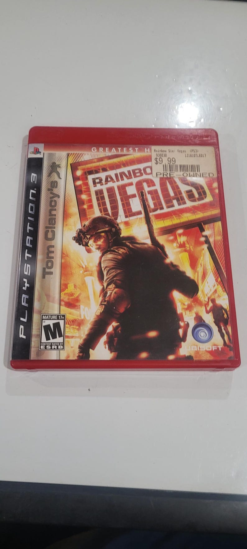 Puede incluir: Caja de juego de PlayStation 3 para Tom Clancy's Rainbow Six: Vegas. La portada presenta a un soldado con equipo t&aacute;ctico con el t&iacute;tulo del juego y la palabra "VEGAS" en letras grandes. La caja es roja.