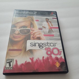 May include: A PlayStation 2 game case for SingStar '80s. The case features a woman wearing sunglasses and a man holding a microphone. The background is pink and features a crowd of people. The game is rated T for Teen by the ESRB.