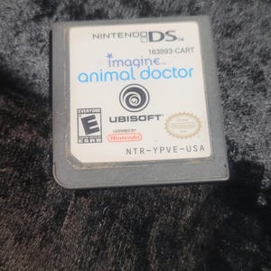 May include: A Nintendo DS game cartridge for "Imagine Animal Doctor." The game cartridge is gray with white text and a logo. The game is rated "E" for Everyone by the ESRB. The game is licensed by Nintendo and published by Ubisoft.