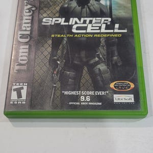 May include: A green Xbox game case for Tom Clancy's Splinter Cell. The cover features a stealth operative in black tactical gear. The game is rated Teen by the ESRB and includes the text "Highest Score Ever! 9.6".