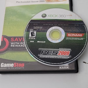 May include: A black Xbox 360 game case with a green and black disc inside. The game case has a white label that says "Pro Evolution Soccer 2009" and a sticker that says "Pre-Owned". The disc has a green label with the text "PES 2009 Pro Evolution Soccer" and a rating of "E for Everyone".