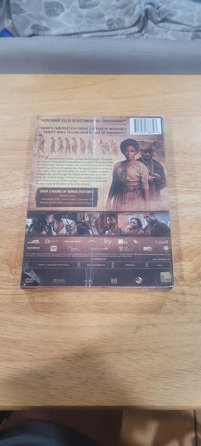 May include: DVD case for "The Book of Negroes" with a woman in a period costume on the cover. The back of the case includes text describing the film's plot and bonus features, with logos from various production companies.