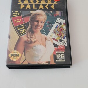 May include: A Sega Genesis game cartridge for Caesars Palace. The front of the cartridge features a woman in a white dress, a roulette wheel, and a playing card. The game is rated MA-13 for Mature Audiences.