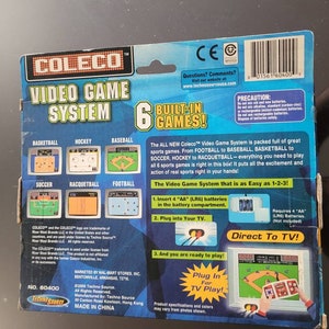 May include: A Coleco Video Game System with six built-in games: Basketball, Hockey, Baseball, Soccer, Racquetball, and Football. The system is blue and yellow and features a plug-in for TV play. The box includes instructions for setting up the system and requires four AA batteries (not included).