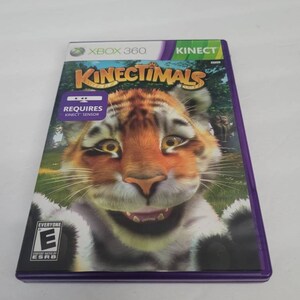 May include: Xbox 360 Kinect game case with a purple border. The front of the case features a cartoon tiger with a toothy grin. The game title "Kinectimals" is printed in large, white letters. The game requires a Kinect sensor.