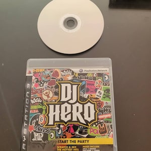 May include: A PlayStation 3 game case for DJ Hero. The case is black with a colorful design featuring the game's logo and characters. The game features a variety of popular music artists and includes a guitar hero controller.