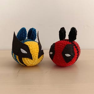 May include: Two crocheted stuffed toys, one yellow and blue with a black mask and the other red with a black mask.